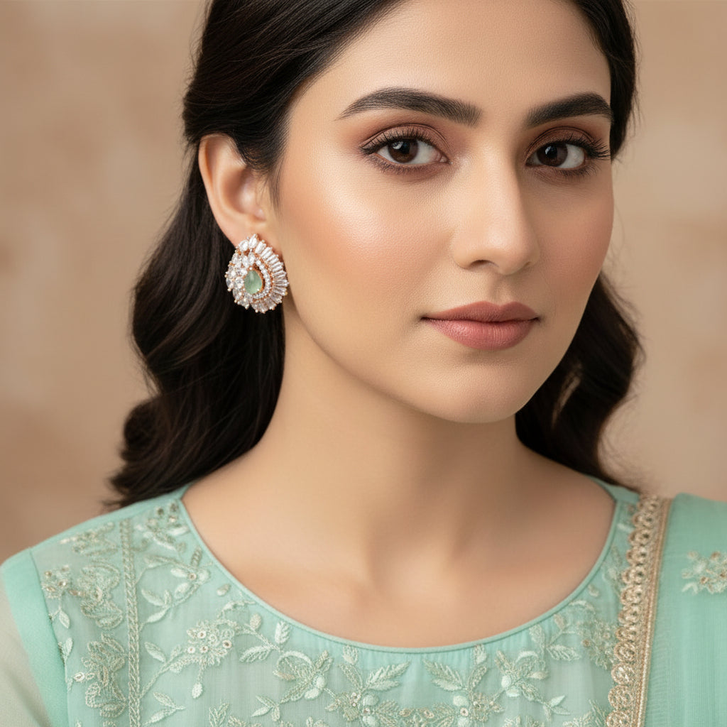 Teardrop-shaped earrings with gemstones on a dark background, featuring the brand 'Saheli'.
