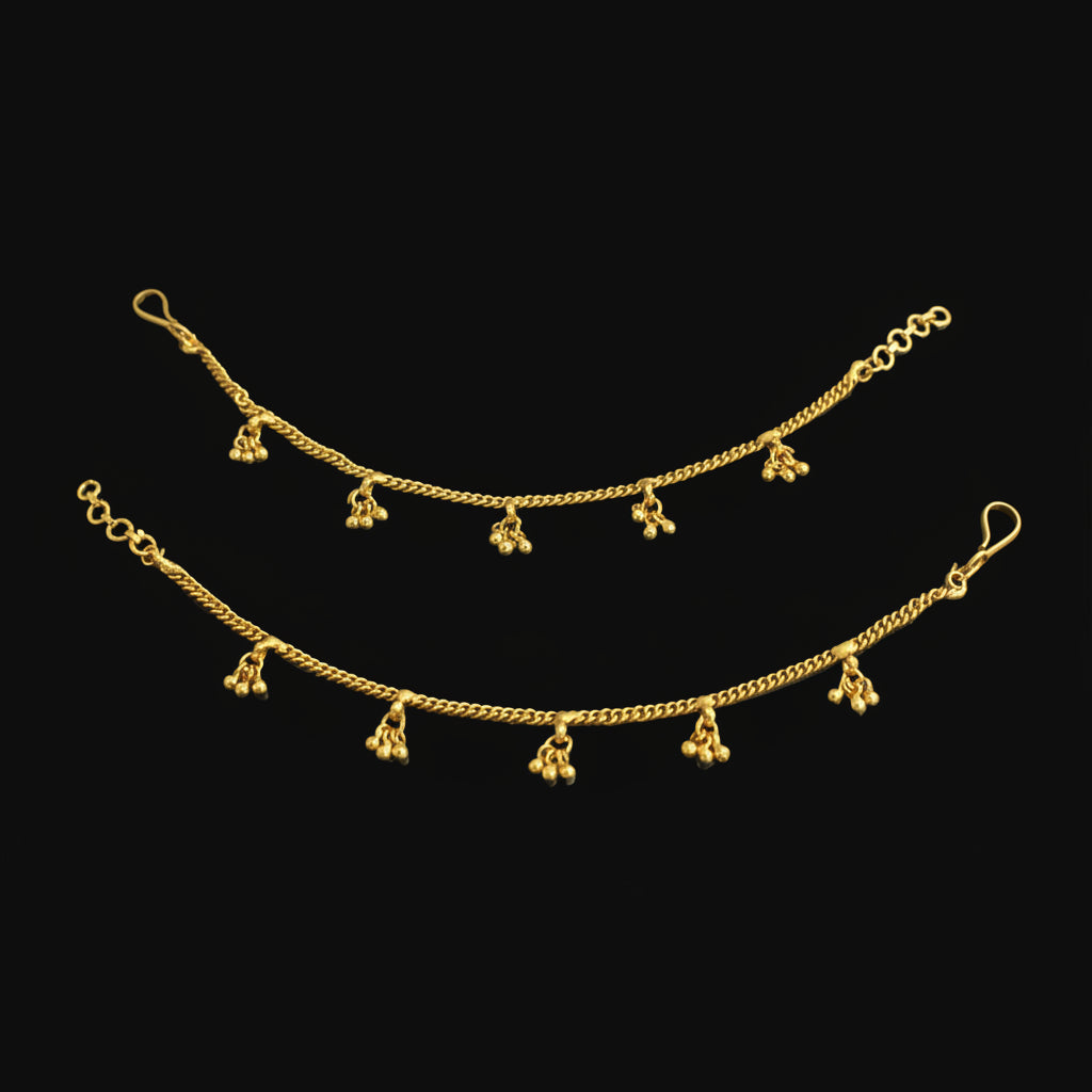 Gold anklets with dangling charms on a black background
