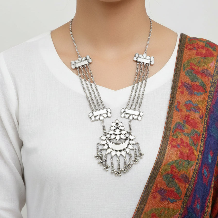Silver necklace with intricate design on a reflective surface
