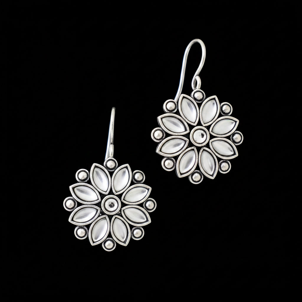 Pair of silver floral earrings on a gray cushion