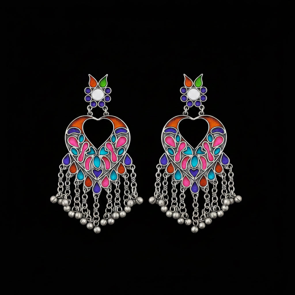 A pair of silver-toned Indian chandbali earrings decorated with vibrant pink, blue, orange, and green enamel, featuring dangling silver bells on a dark reflective surface.