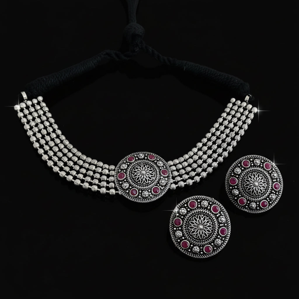 Silver necklace with red gemstones on a dark surface
