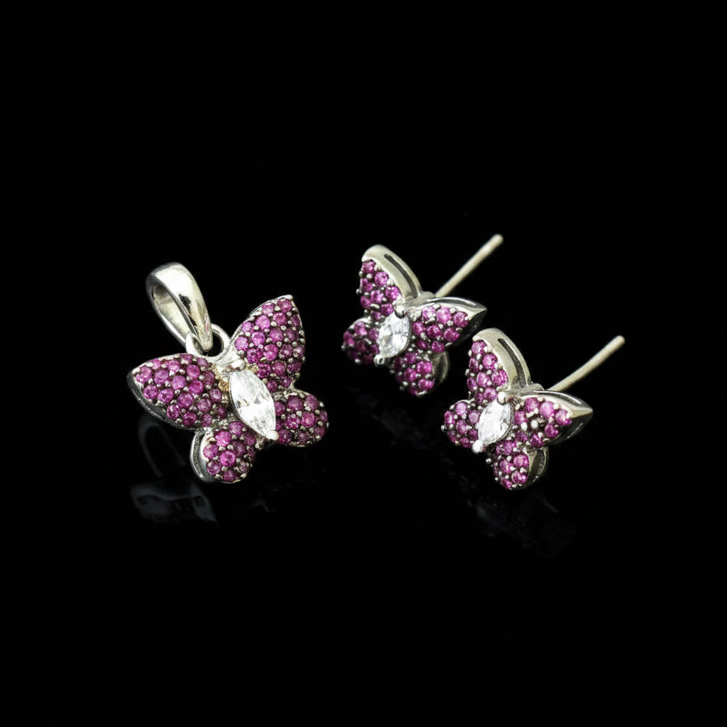 Butterfly-shaped earrings with pink gemstones on a gray background, featuring the brand 'SAHELI'.