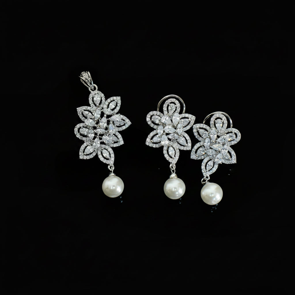 Silver floral earrings with pearl drops on a dark background, branded 'SAHELI'.