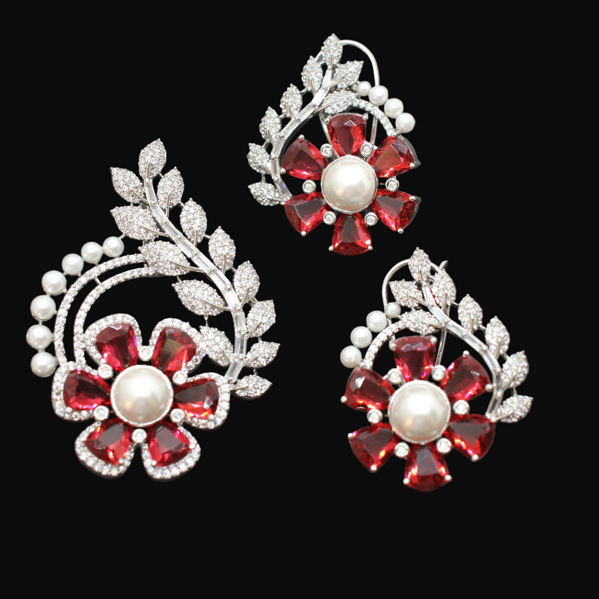 Three pairs of red and silver floral earrings on a dark gray background