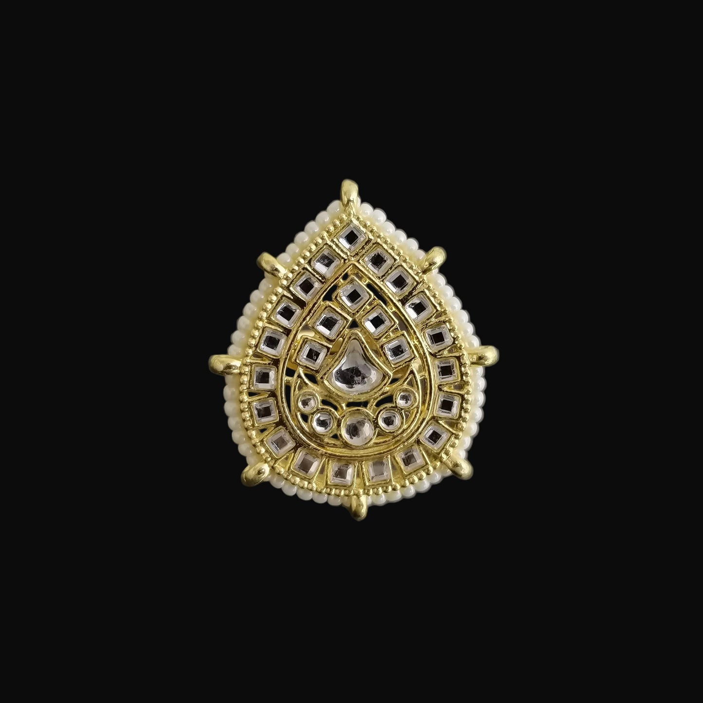 Gold and silver teardrop-shaped jewelry piece on a dark background