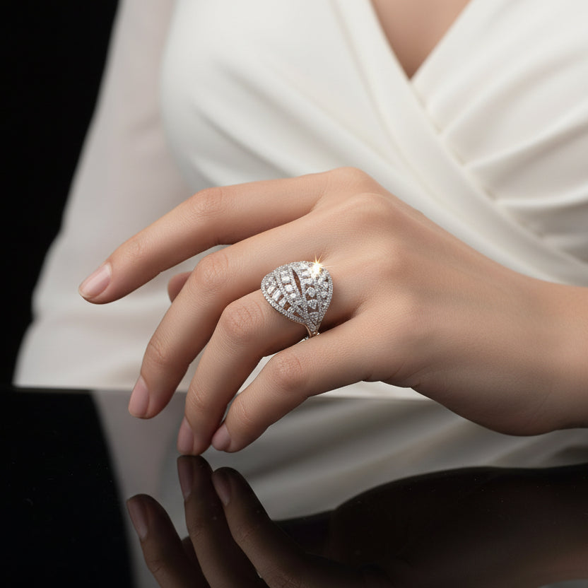 Silver ring with intricate design on a gray background, featuring the brand 'Saheili'.