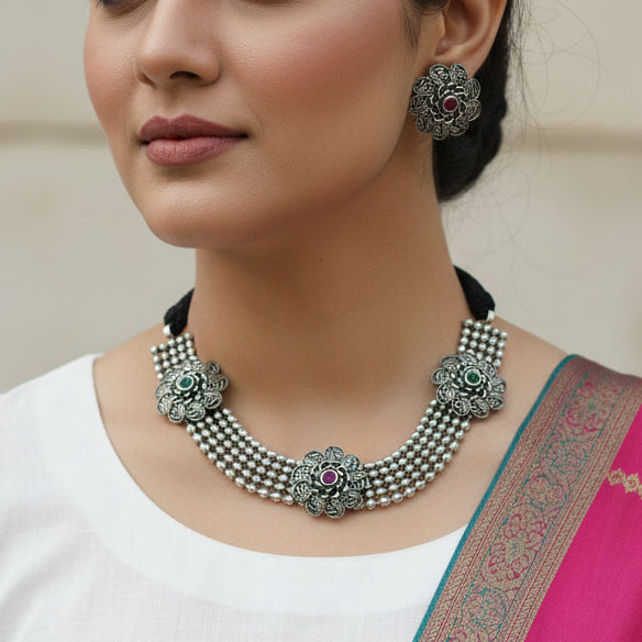 Silver necklace and earrings set on a dark background