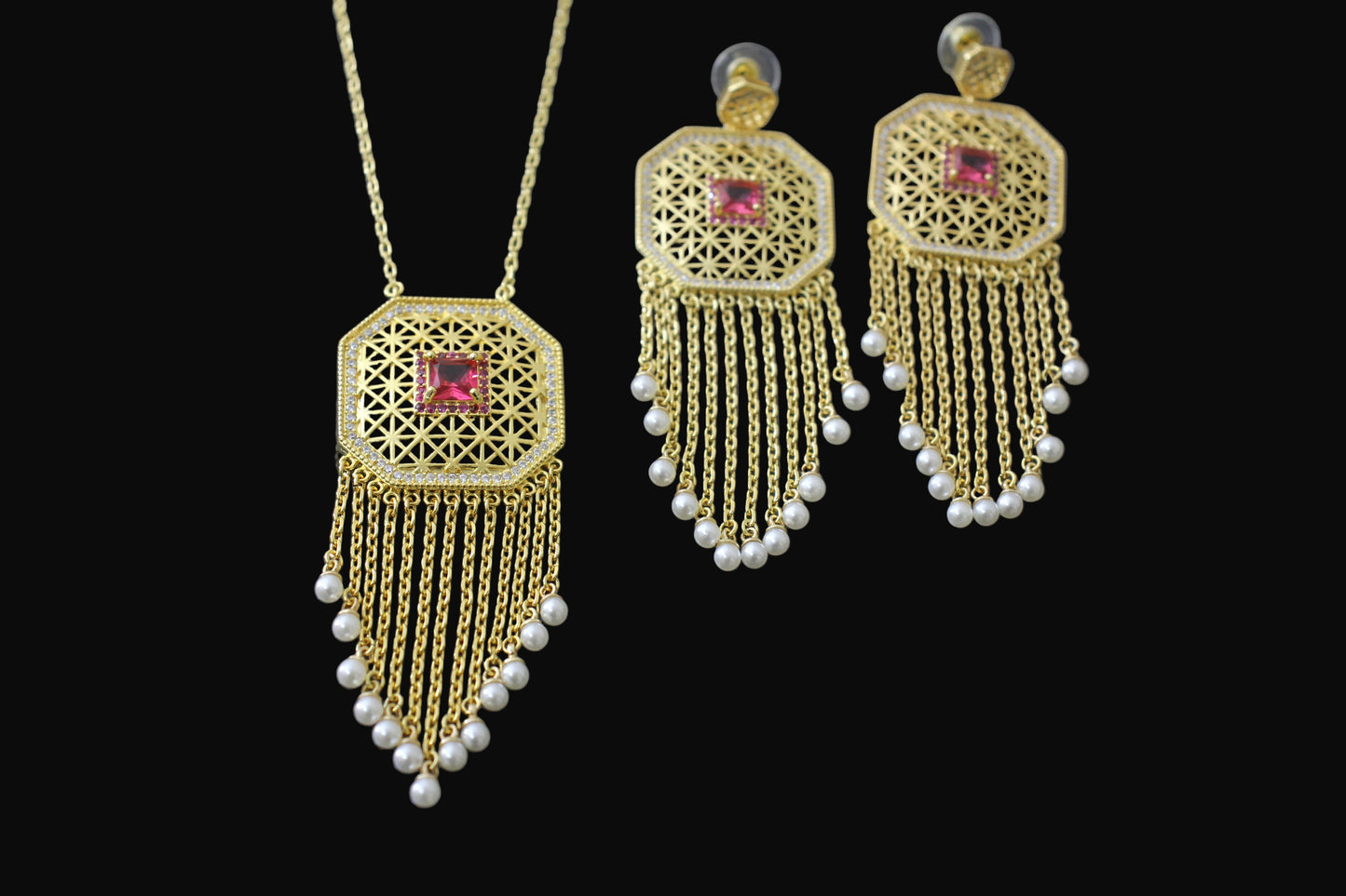 Gold necklace and earrings with red gemstones on a dark background