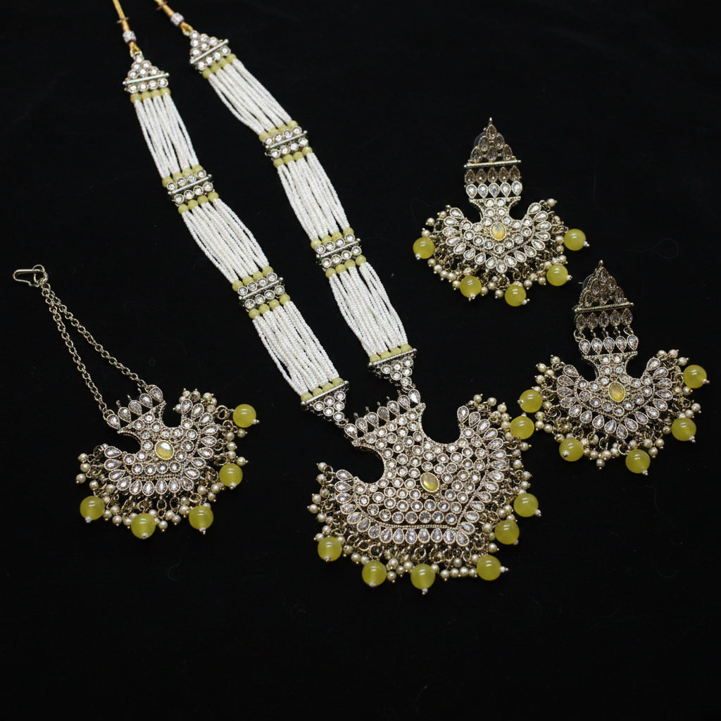 Ornate jewelry set with yellow beads on a dark background
