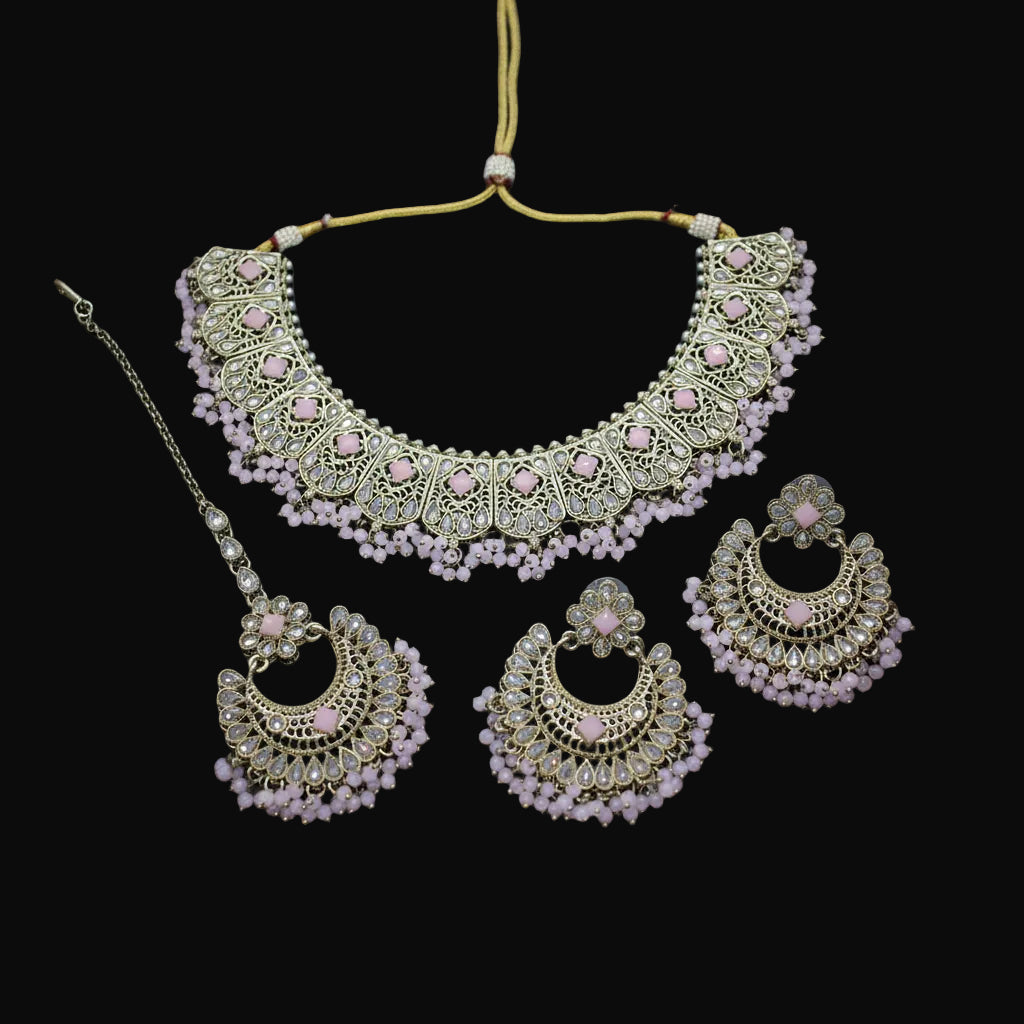 Ornate gold and pink jewelry set on a dark background