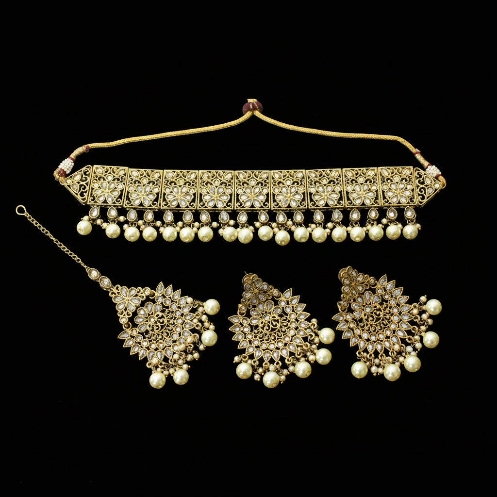 Gold-plated Indian bridal jewelry set featuring a choker necklace, a matching pendant, and a pair of large dangle earrings, embellished with white faux pearls and set against a dark reflective background. The brand logo 'SAHELL MY BEST FRIEND' is visible in the bottom-left corner.