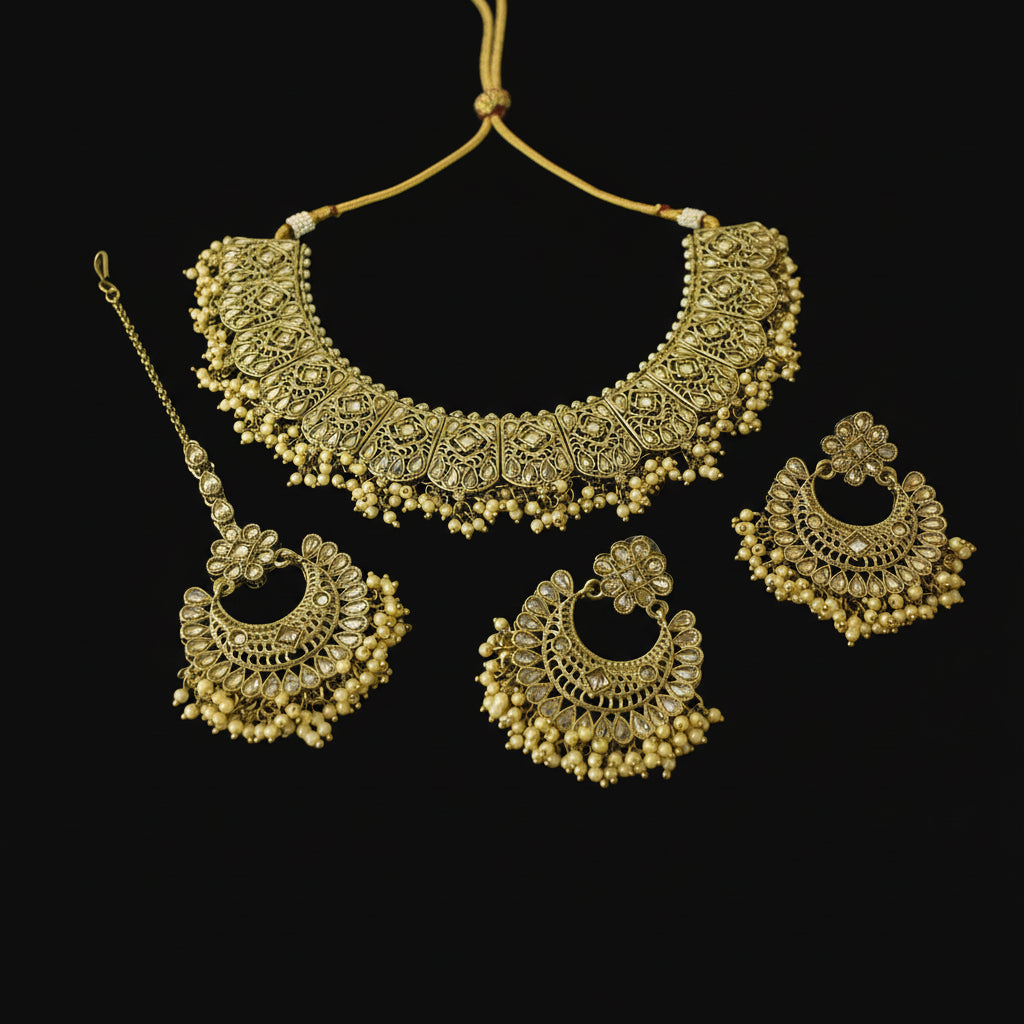 Gold jewelry set with necklace, earrings, and maang tikka on a black background
