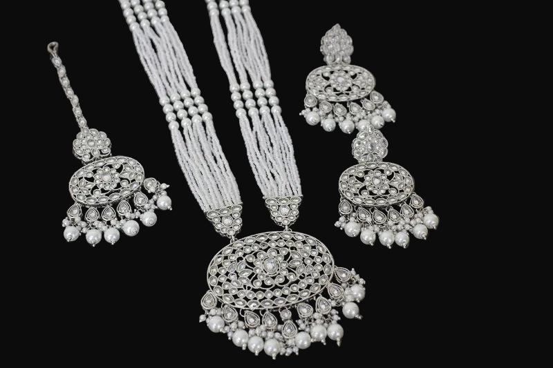 Silver jewelry set with necklace, earrings, and bangles on a black background