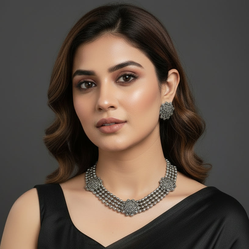 Silver beaded necklace with matching earrings on a reflective surface