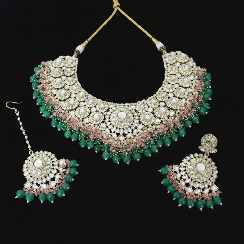 Ornate necklace and earrings set with green and pink stones on a dark background