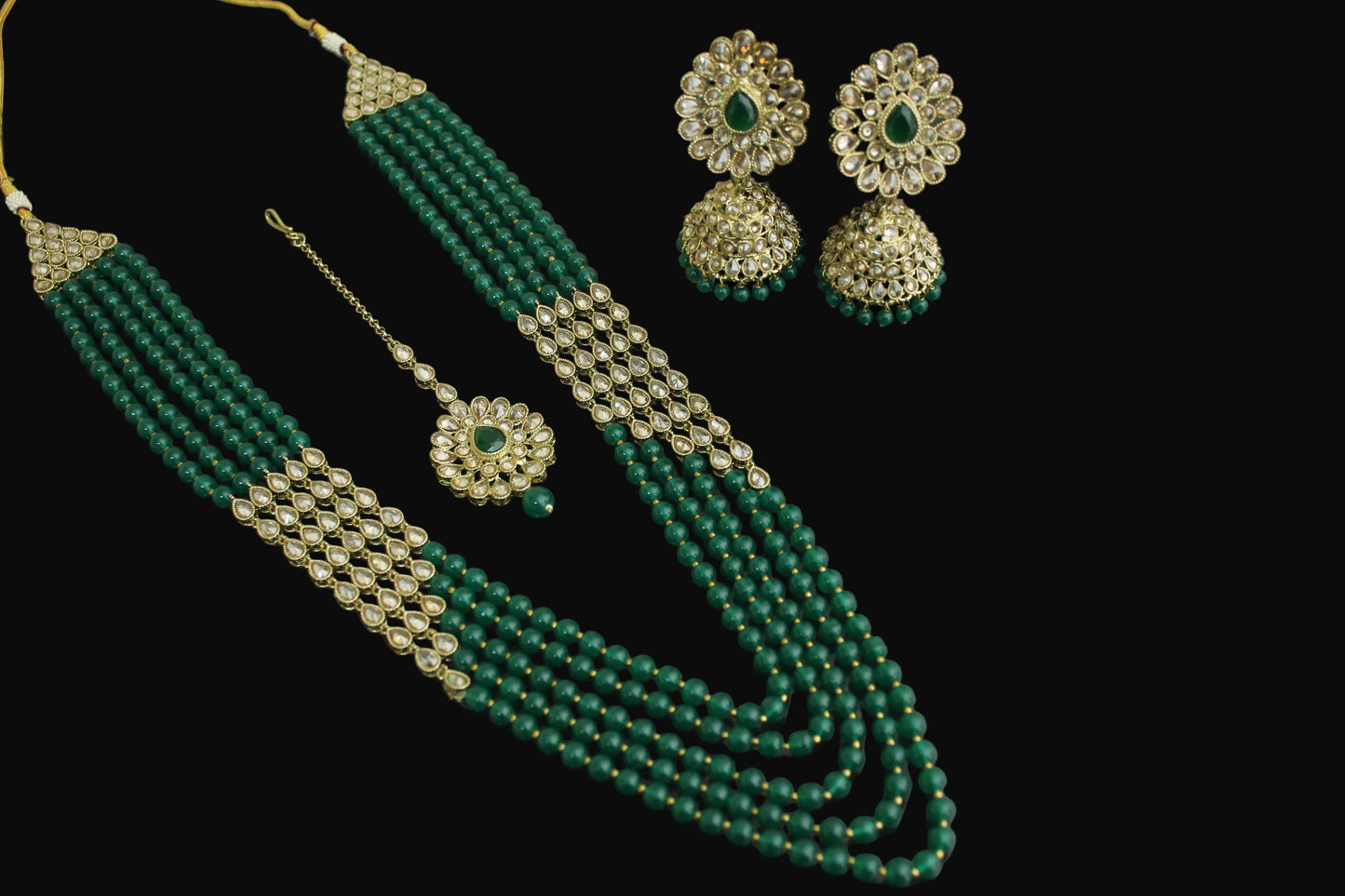 Green beaded necklace with gold accents and matching earrings on a dark background