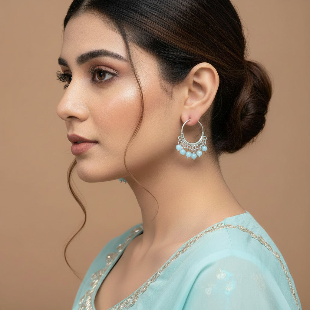 Pair of silver hoop earrings with blue gemstones on a brown background