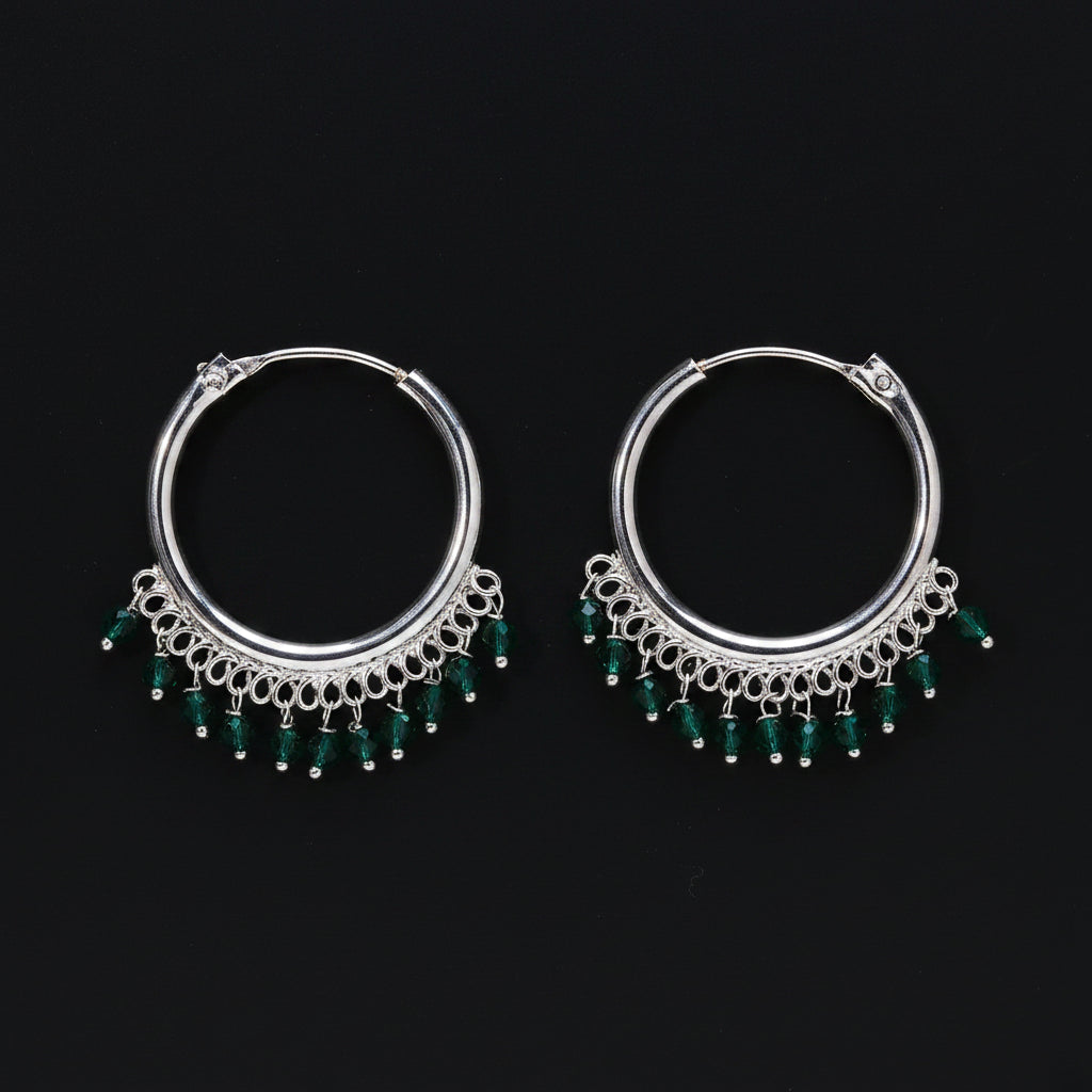 Pair of silver hoop earrings with green beads on a brown background