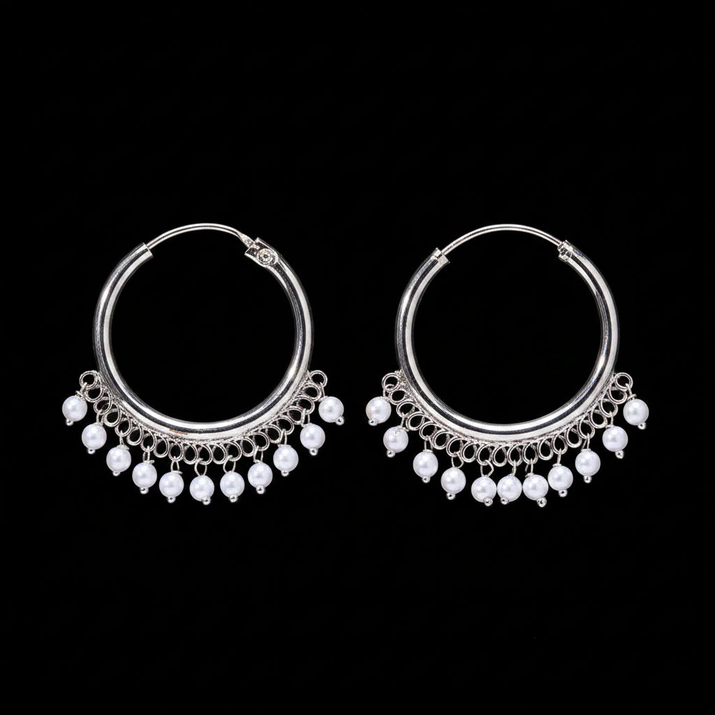 Pair of silver hoop earrings with pearl-like beads on a brown background
