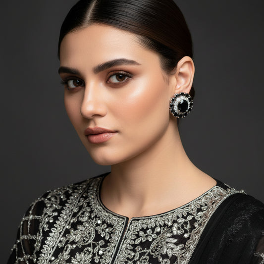 Pair of black gemstone earrings with silver accents on a red background