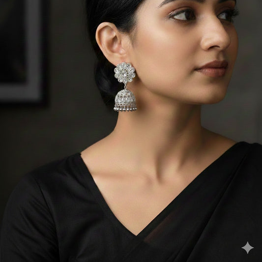Woman wearing a black saree with a large, ornate earring on a dark background
