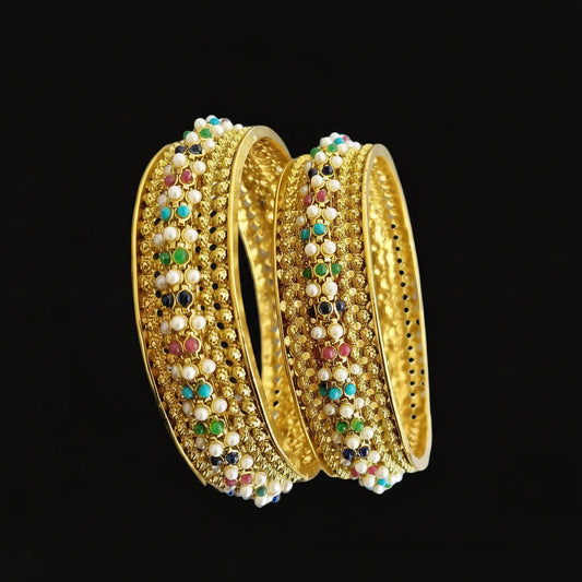 Gold bangles with colorful stones on a gray background, featuring the brand 'Saheli'.