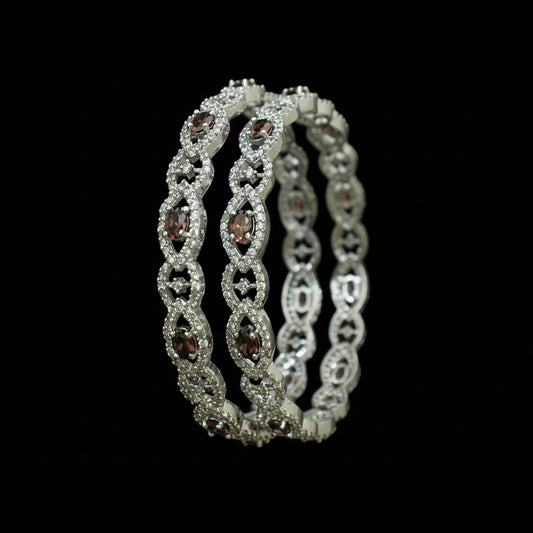 Silver bangles with gemstones on a black background, featuring the brand 'Saheli'.