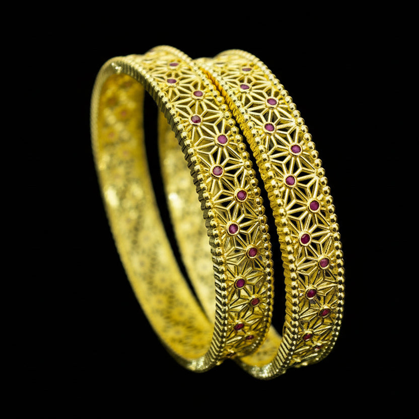 Gold bangles with intricate designs on a dark background