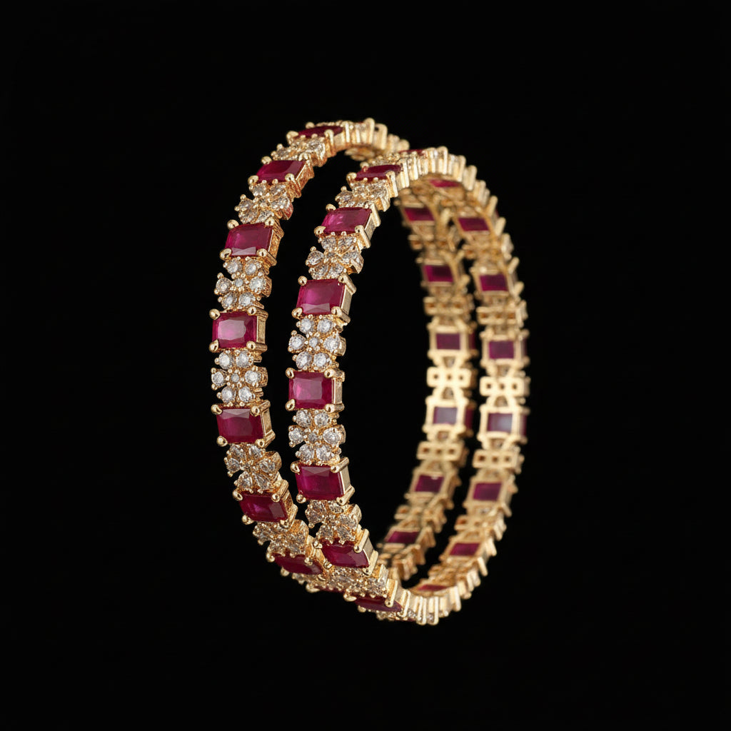 Gold bangles with red gemstones on a dark background
