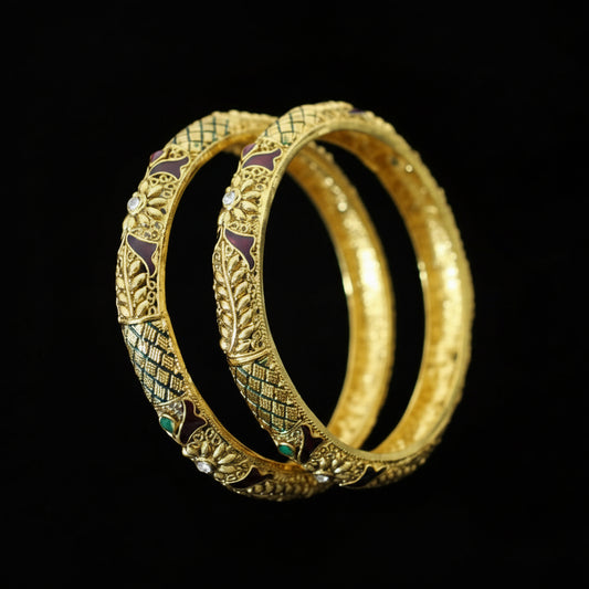 Gold bangles with intricate designs on a gray background, featuring the brand 'SAHELLI'.