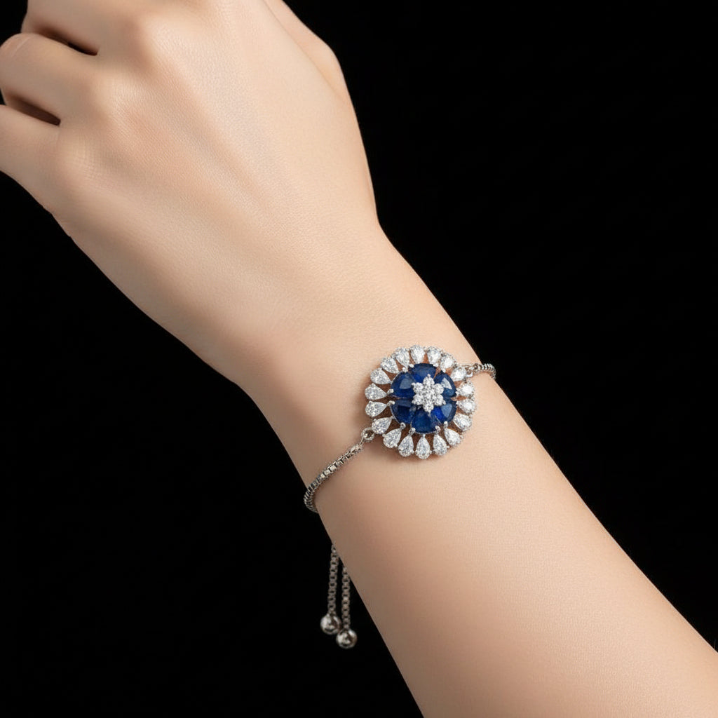 Silver bracelet with a blue gemstone on a dark background, featuring the brand 'Saheli'.