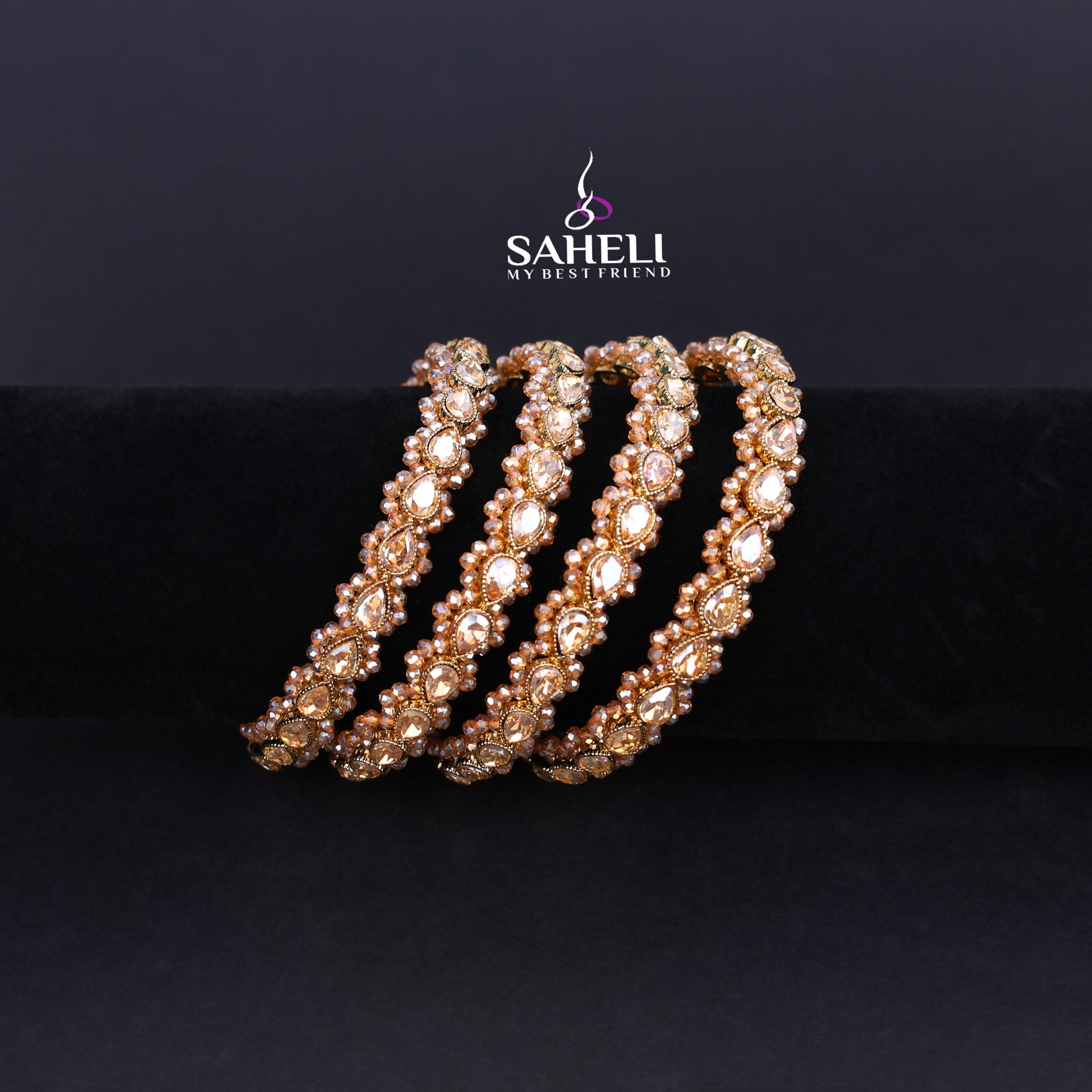 Decorative bracelet with rose gold accents on a black background, featuring the brand 'SAHELI'.