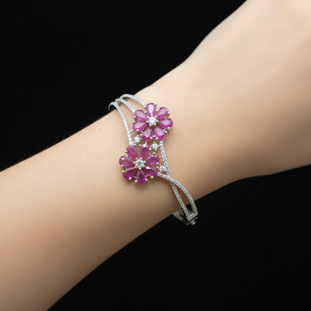 Silver bracelet with pink gemstone flowers on a gray surface