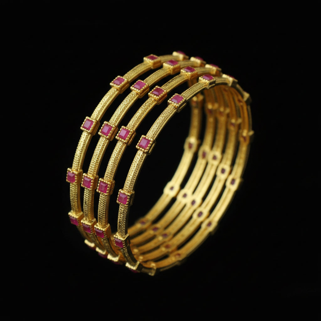 Set of gold bangles with red stones on a black stand, branded 'Saheli'.