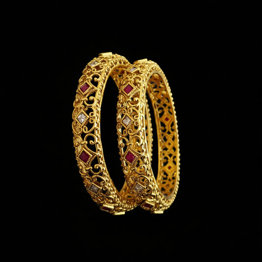 Gold bangles with red stones on a gray background, featuring the brand 'SAHELLI'.