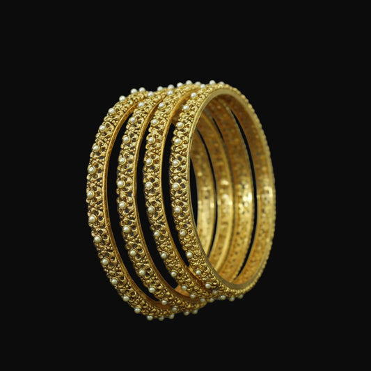Gold bangles on a black stand with 'Saheli' branding in the background