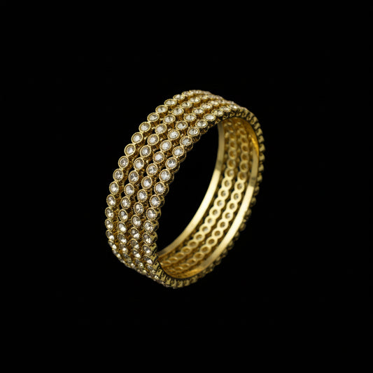 Gold bracelet on a gray stone surface with a dark background
