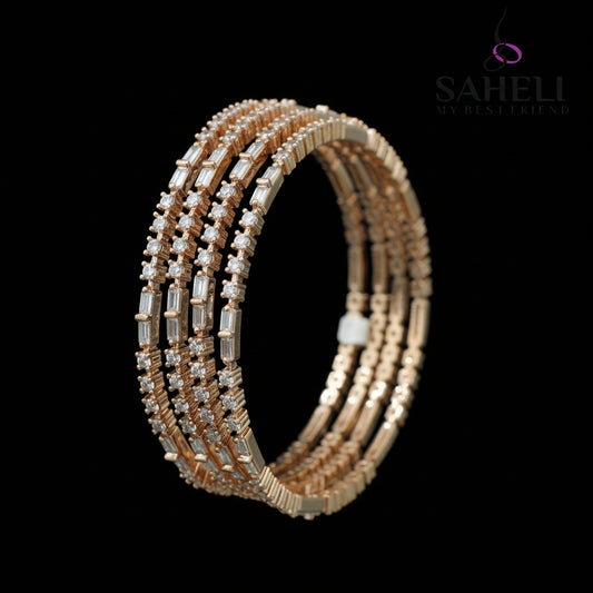 Gold bangles with clear stones on a black background, branded 'Saheli'.