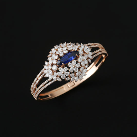 Elegant bracelet with floral design and blue gemstone on a wrist against a black background