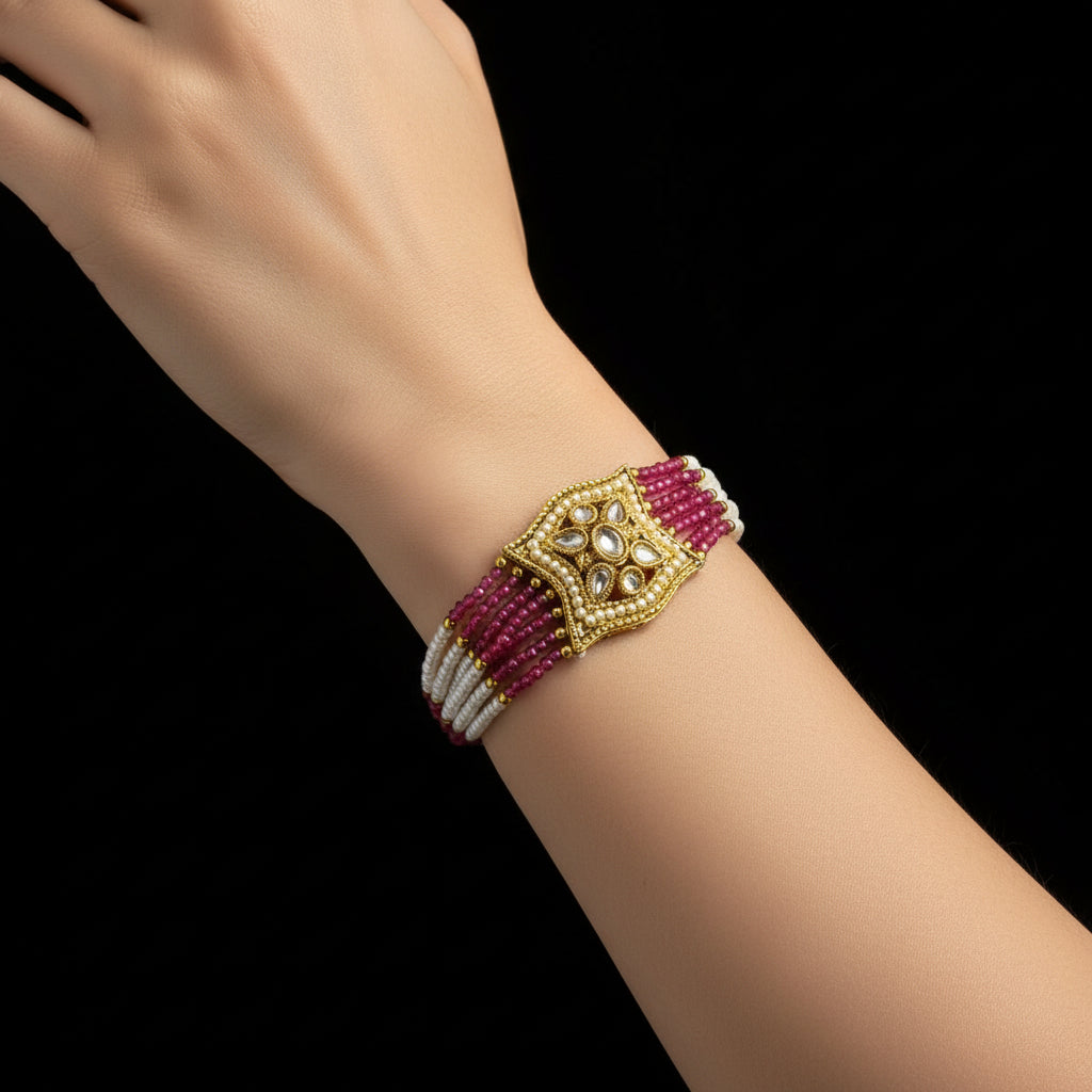 Bracelet with gold clasp and pink and white beaded strands on a dark background, featuring the brand 'Saheeli'.