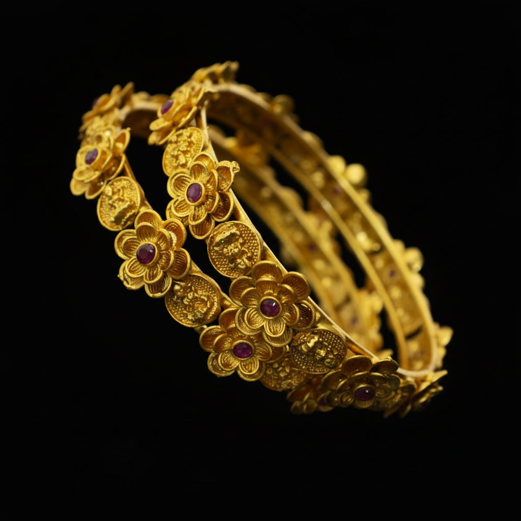 Gold bracelet with floral designs and red stones on a dark background, featuring the brand 'SAHELI'.