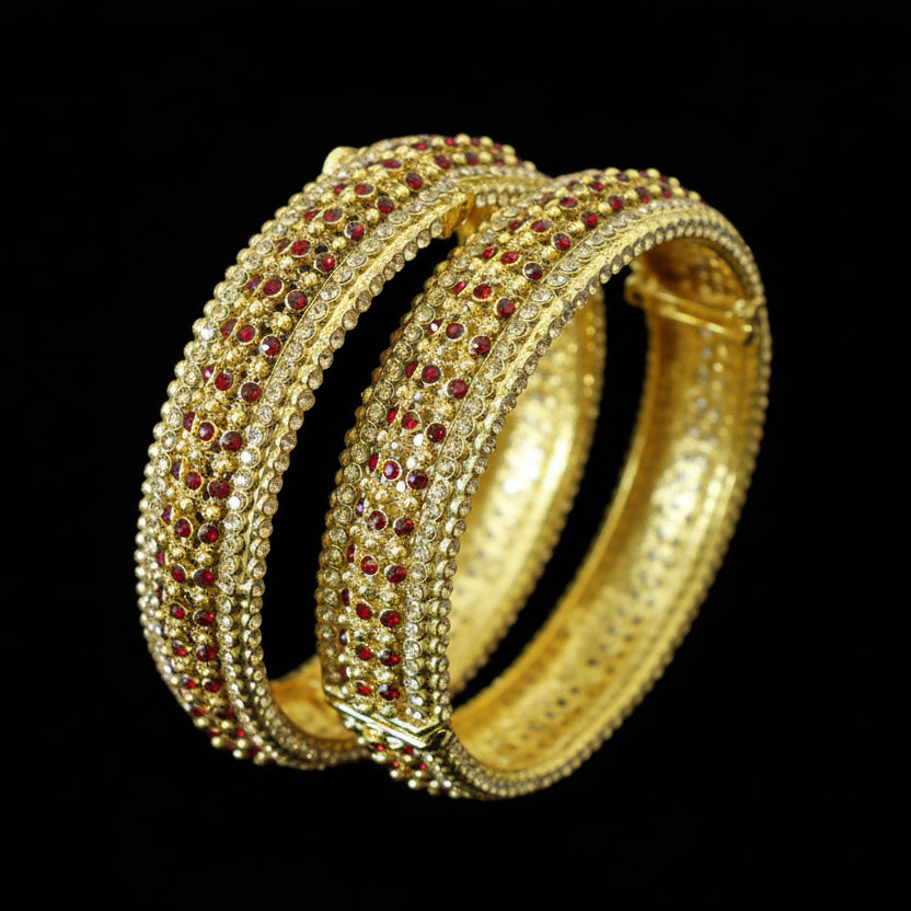 Gold bangles with red stones on a stand, branded 'Saheli'.
