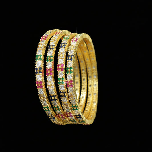 Gold bangles with colorful stones on a dark background, branded 'Saheli'.
