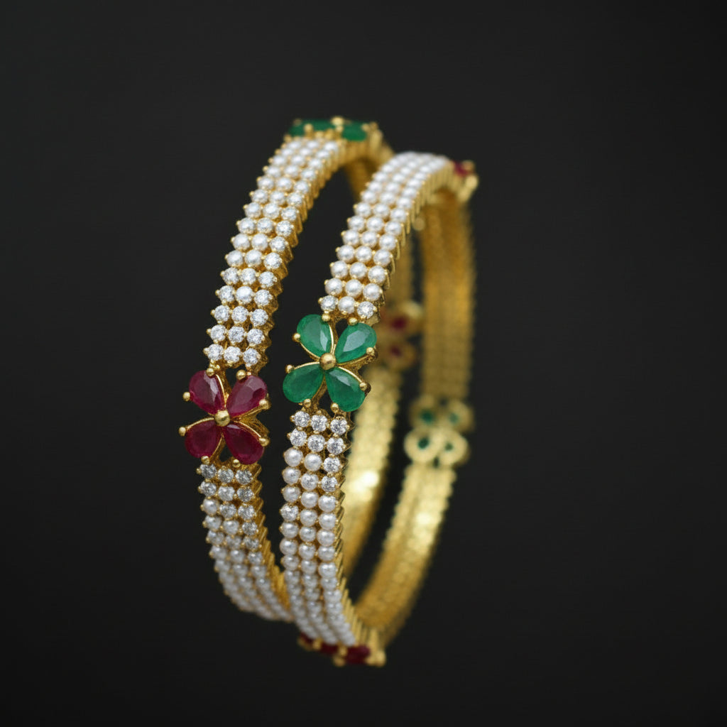 Gold bangles with gemstones on a dark background, featuring the brand 'Saheli'.