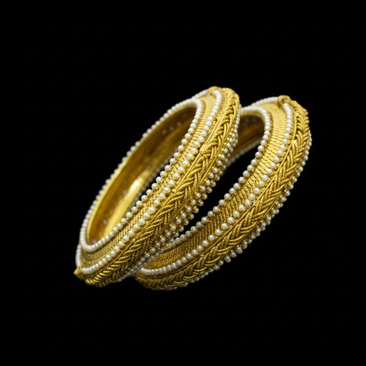 Gold and pearl bangles with 'SAHELI' branding on a dark background