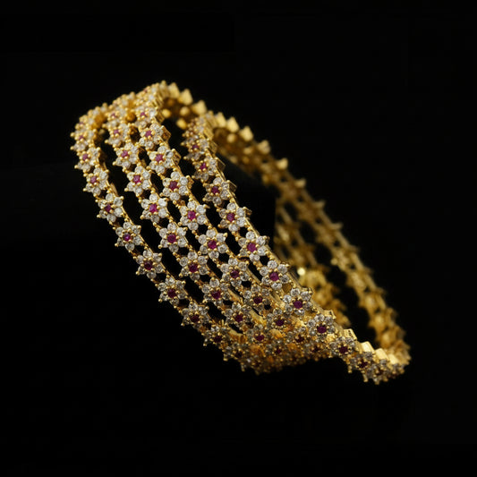 Gold bracelet with red stones on a dark background, featuring the brand 'Sarehli'.