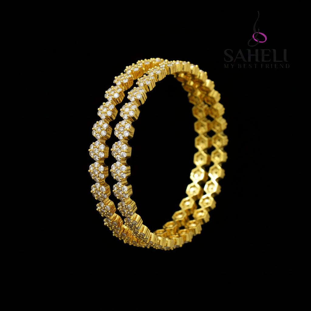 Gold bangles with intricate design on a black background, featuring the brand 'Saheli'.