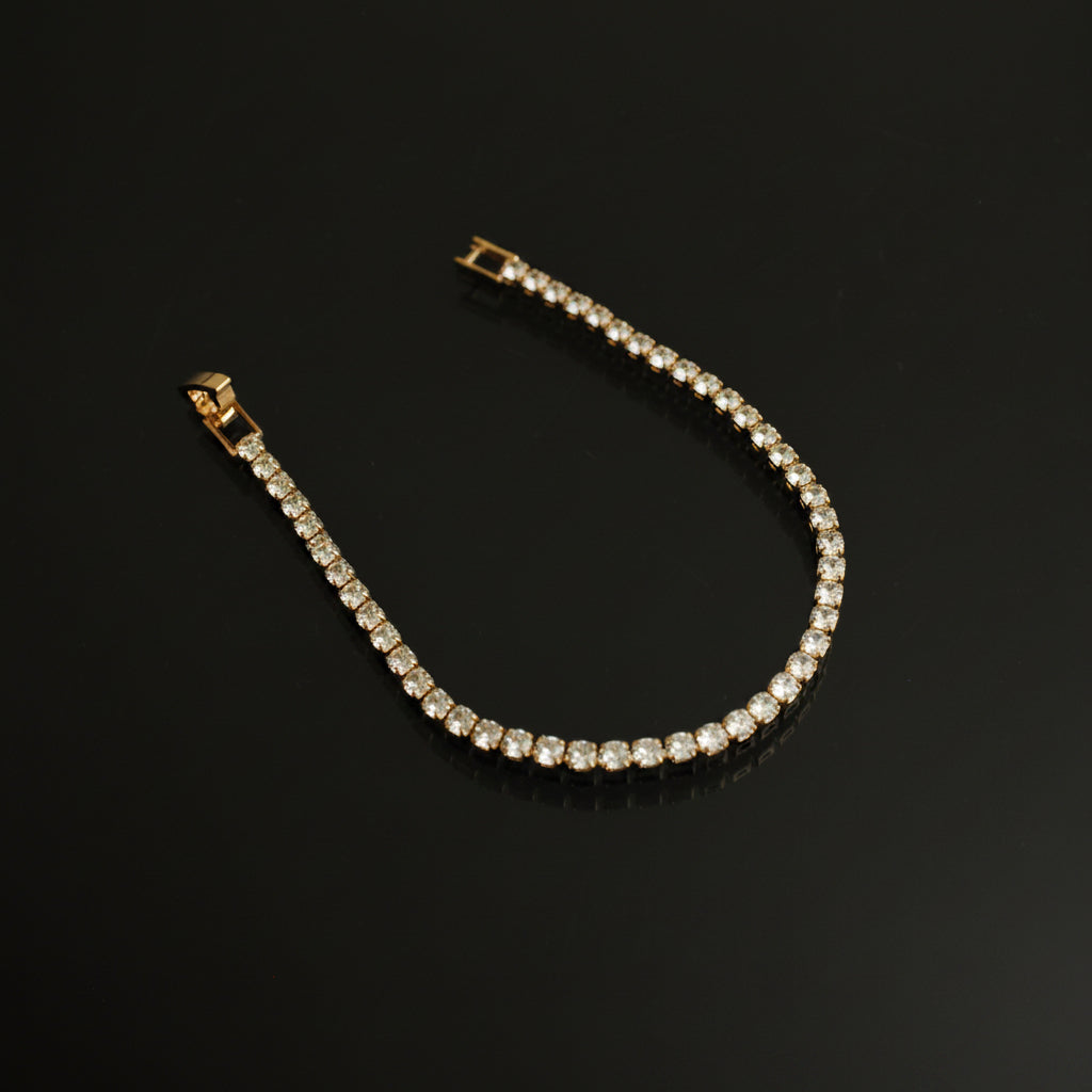 Gold bracelet with clear stones on a black background