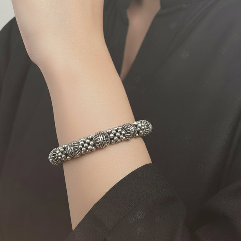 Silver bangles with jhumkas on a black background, featuring the brand 'Saheli'.